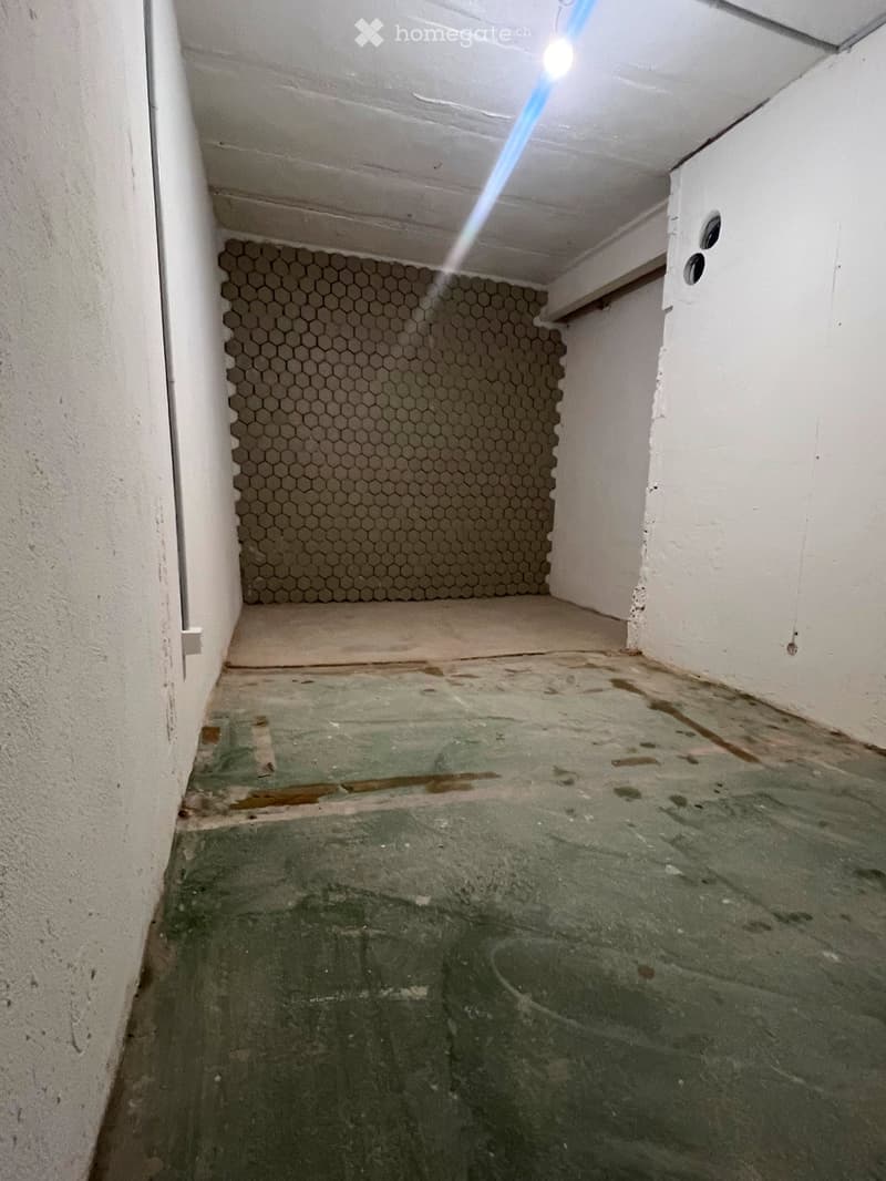 Empty room with hexagonal tile backsplash, concrete floor, and white walls.