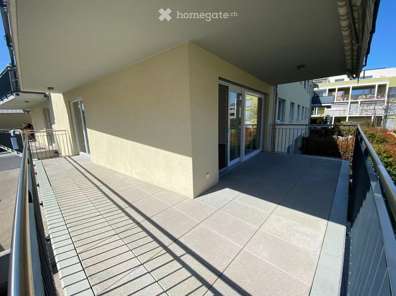 Balcony with tiled floor, metal railings, and glass doors leading to the interior.