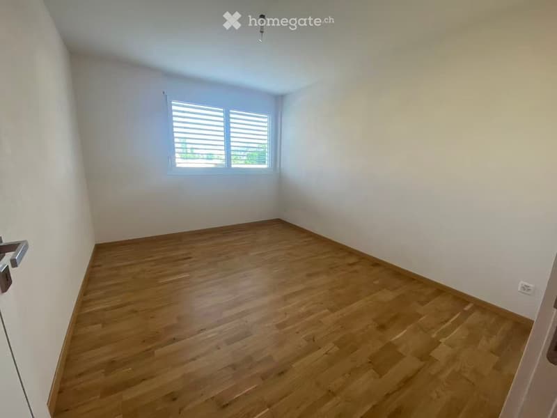 Empty room with wooden flooring, white walls, and a window with blinds. No furniture or equipment is present.