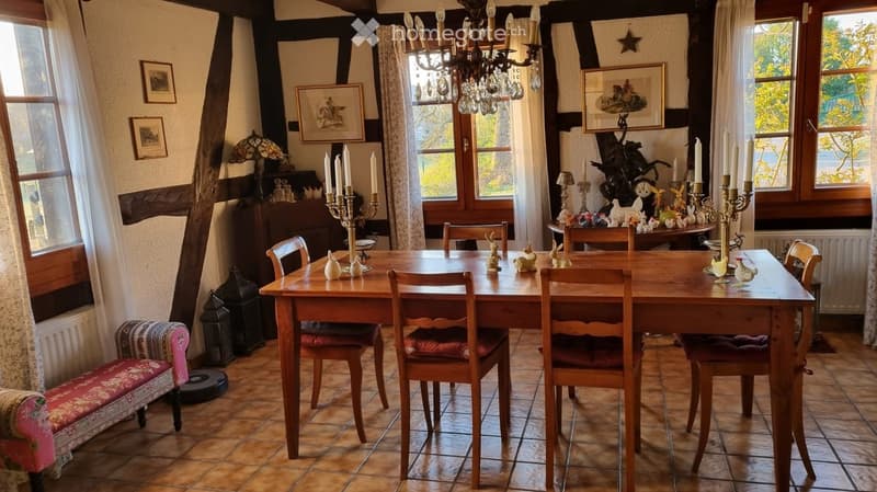 Cozy dining room with wooden dining table, chairs, bench, chandelier, table lamp, candle holders, framed pictures, and curtains.