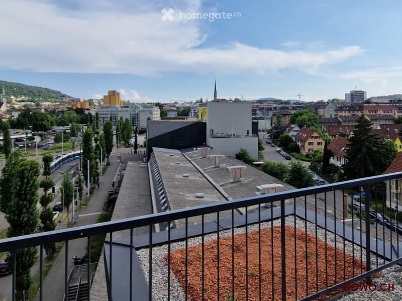 Balcony overlooking a cityscape with buildings, trees, and a road below.