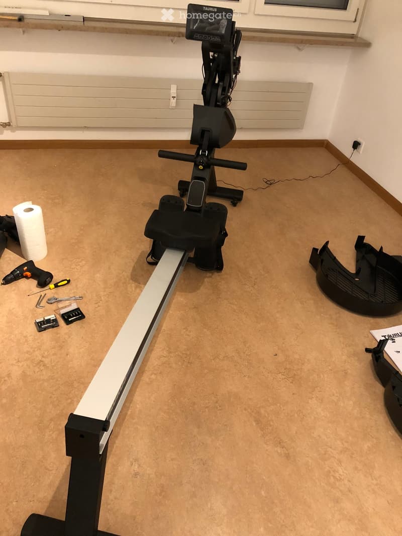 Room with a fitness bike, tools, and a paper towel roll on the floor.