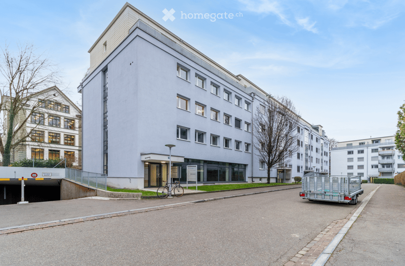 Multi-story residential building, grey exterior, glass windows, ground floor access, bicycle parked outside