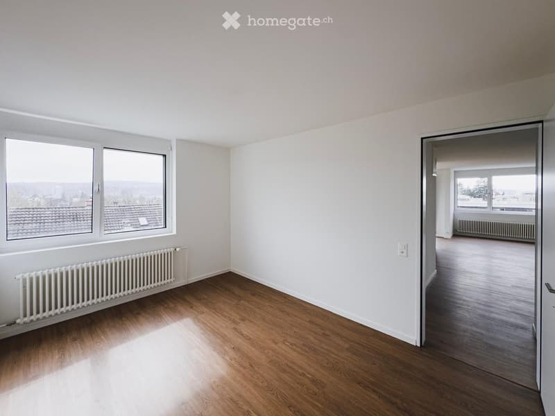 Empty room, wooden floor, large window, radiator, wooden door