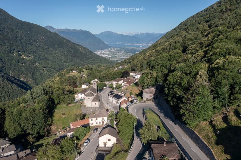 mountain village, traditional houses, solar panels, curvy road, lush green landscape