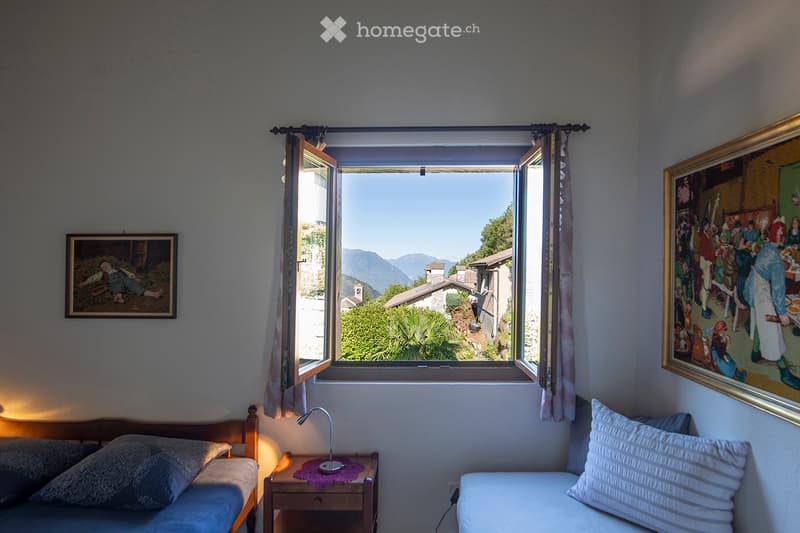 room with double bed, desk with lamp, painting, window with valley view