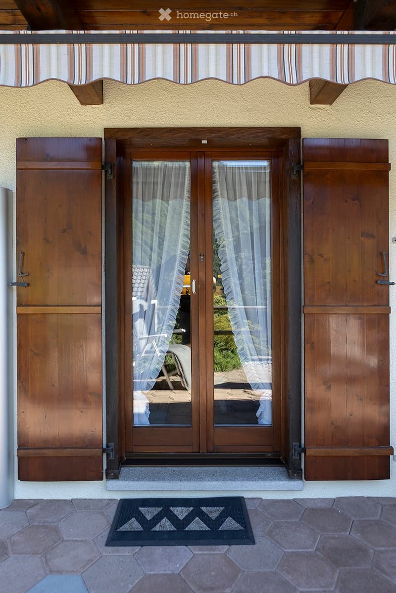 Exterior entrance, wooden double doors, striped awning, wooden shutters, hexagonal stone flooring