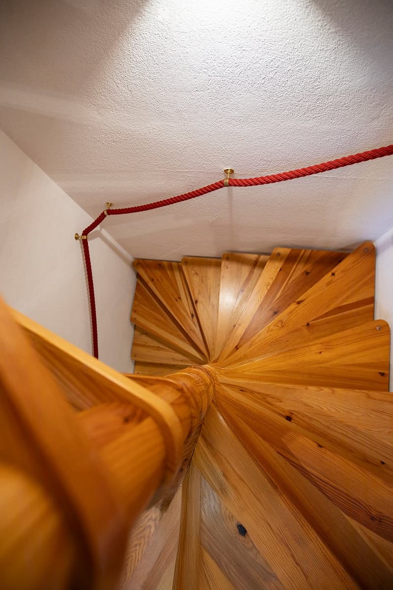 wooden spiral staircase with red rope handrail