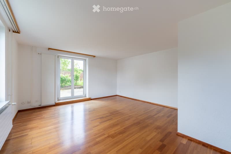 Empty room with wooden flooring, white walls, and large windows with blinds. No furniture or equipment present.