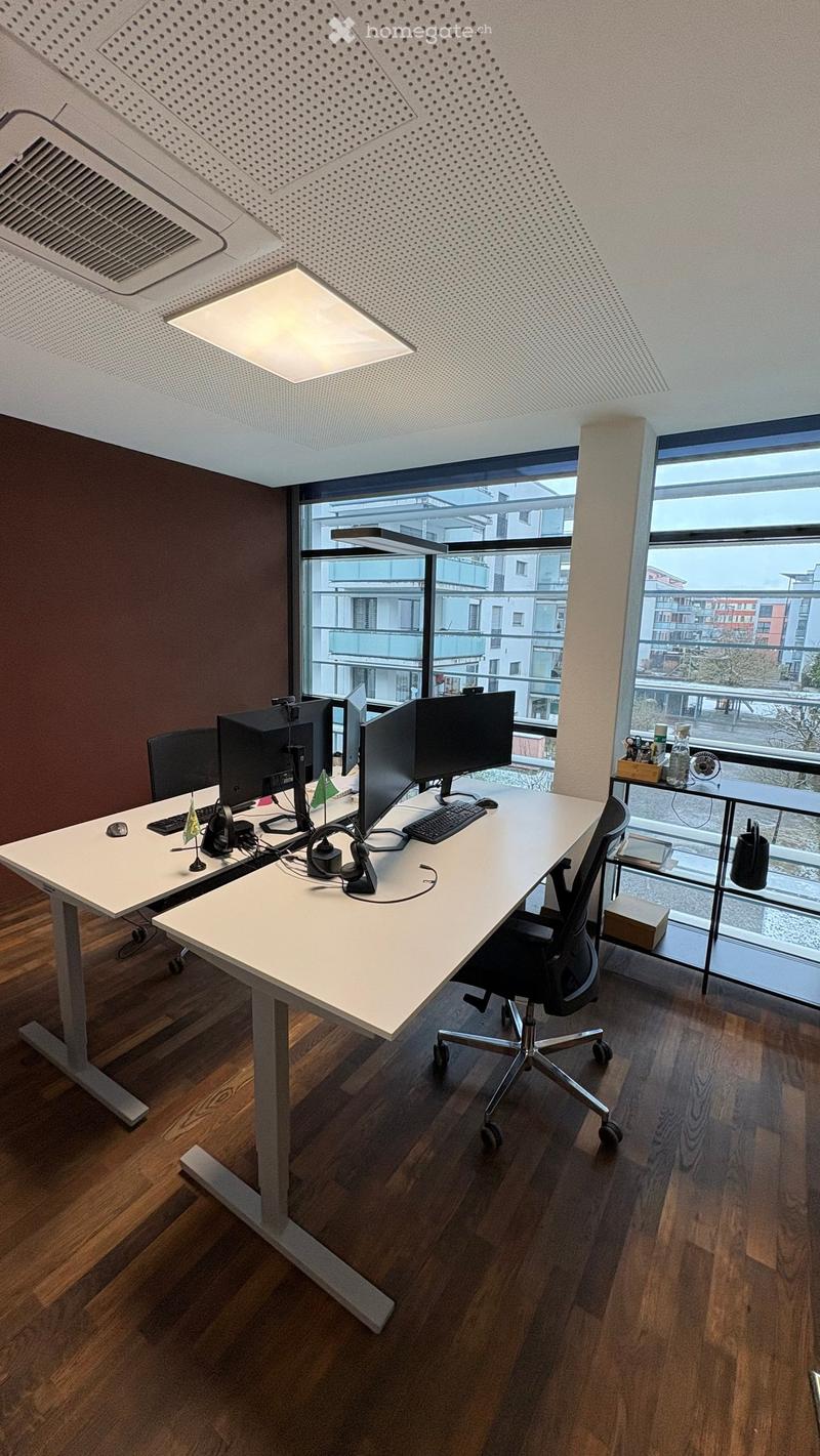modern office with two desks, two chairs, computer monitors, keyboards, mice, headphones, flags, wooden floor, large windows, city view