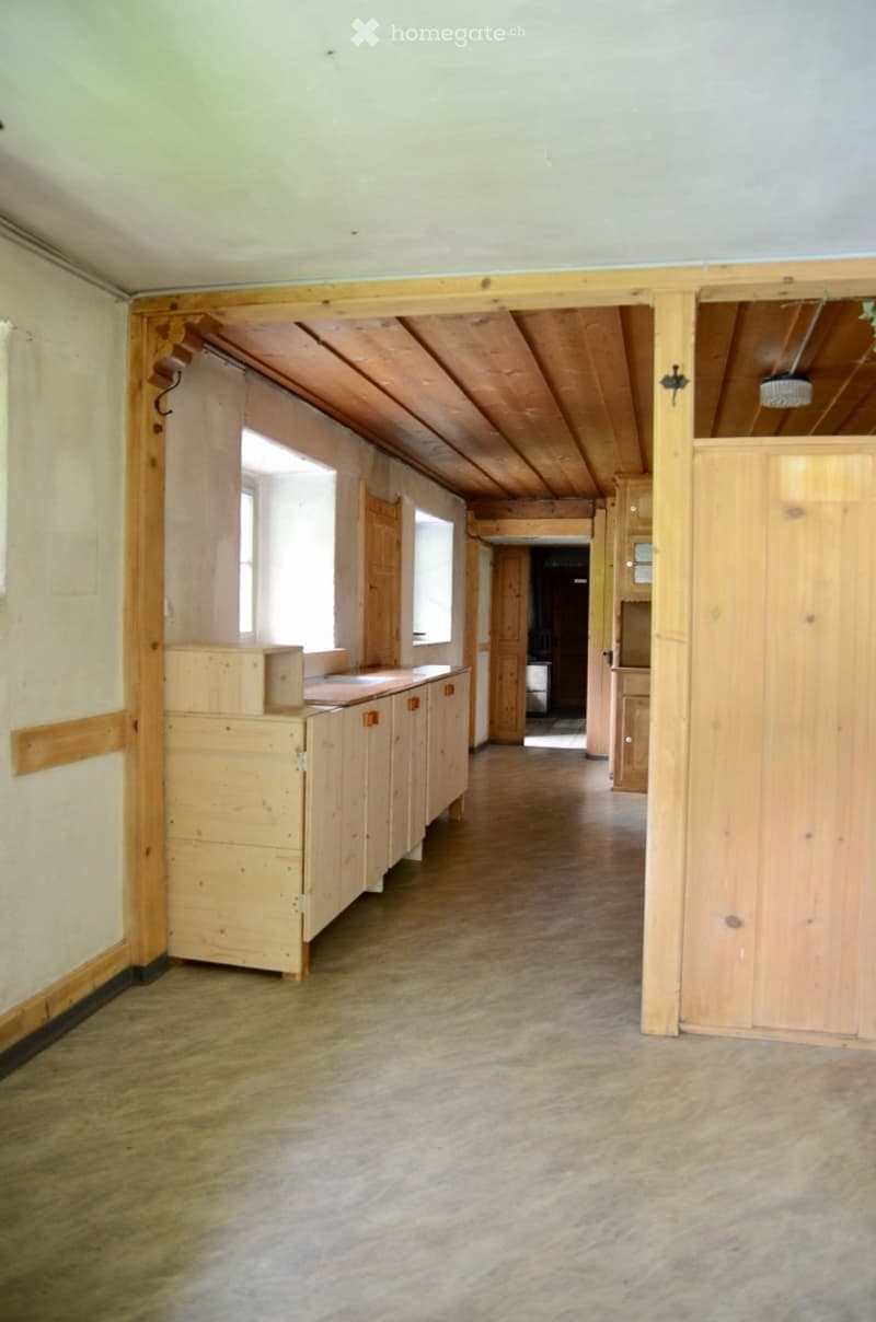 Empty room with wooden floor, exposed wooden beams, and unfinished wooden cabinetry. No furniture or equipment present.