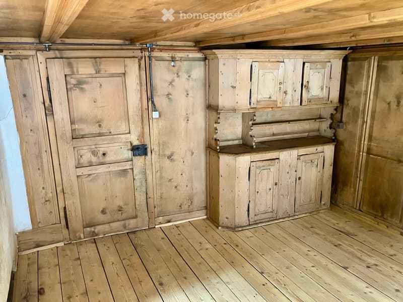 Empty room with wooden walls, wooden floor, and built-in wooden cabinetry with drawers and shelves.