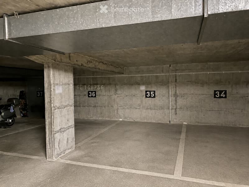 Underground parking area with numbered spaces, concrete pillars, and a scooter parked in the background.