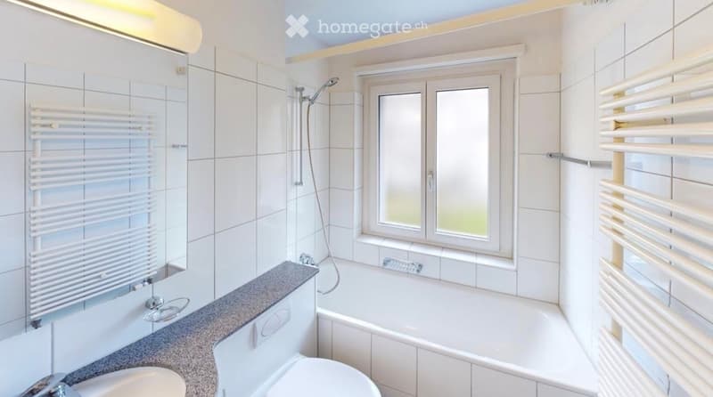Modern bathroom with white tiles, a bathtub, toilet, shower, and radiators on both sides of the room.