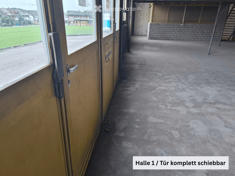 Empty concrete hallway with a sliding door on the left and a staircase leading upwards on the right.