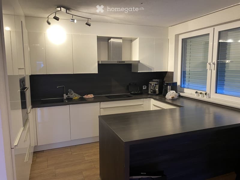 Modern kitchen with white cabinets, stainless steel appliances, and a dark countertop island.