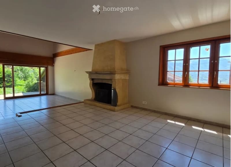 Empty living room with tiled floor, fireplace, large windows offering a scenic view, and sliding glass doors leading to an outdoor area.