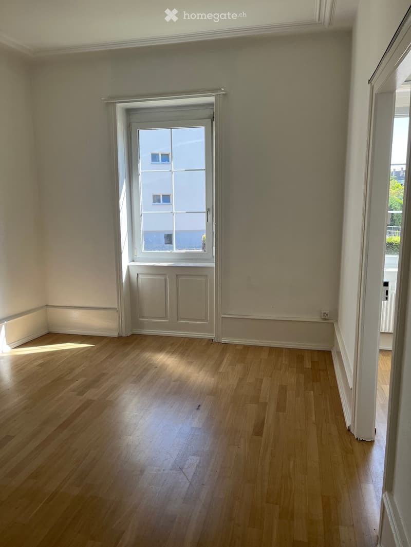 Empty room with wooden flooring, light-colored walls, and a door leading to an outdoor area.