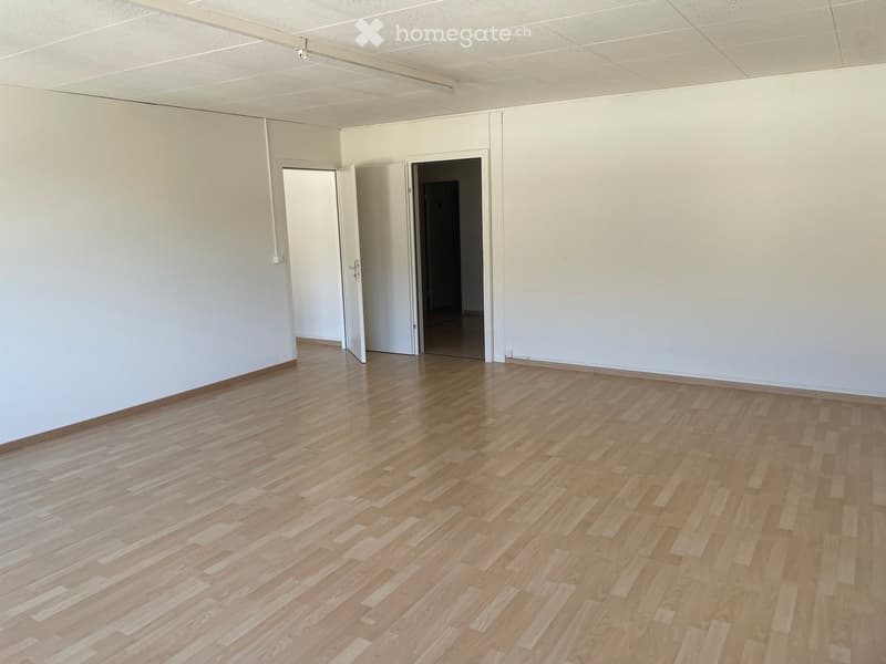 large empty room, white walls, wooden floor, two open doors