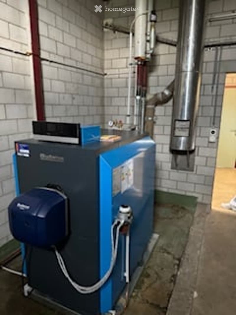 Other. A modern boiler unit with a control panel, installed in a utility room with brick walls and metal pipes.