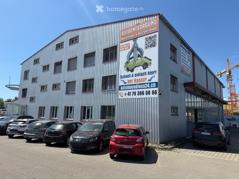 A commercial building with a large sign advertising car services, surrounded by parked cars.