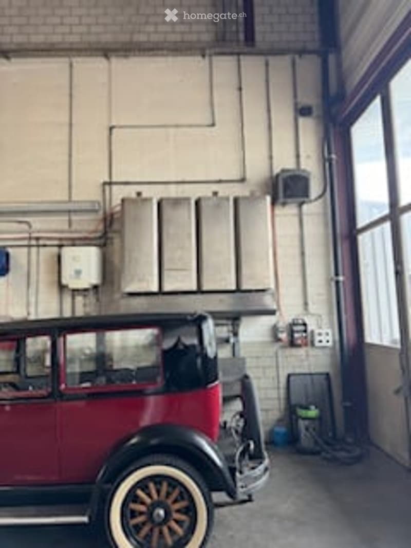 Classic car parked in a garage with white brick walls and visible electrical installations.