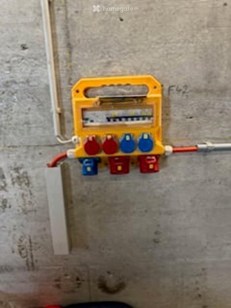 Other. A water meter with multiple valves mounted on a concrete wall, featuring a yellow casing and blue and red valve handles.