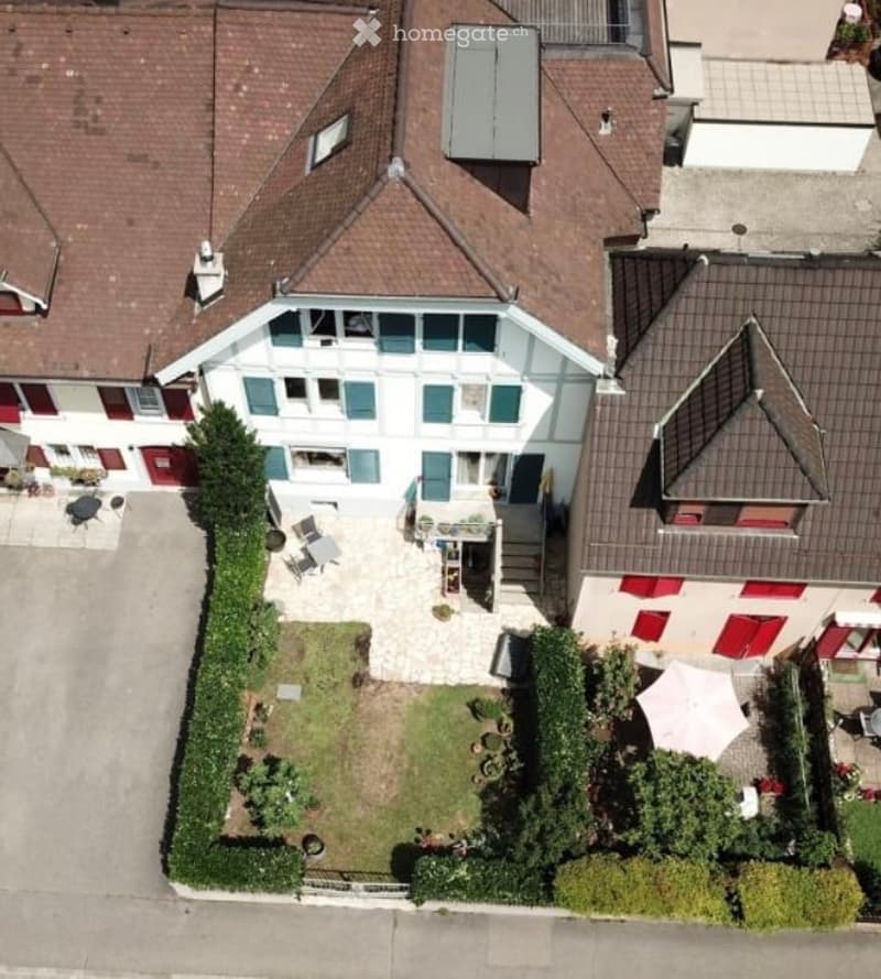 Aerial view of a multi-story residential building with a well-maintained garden and patio area.
