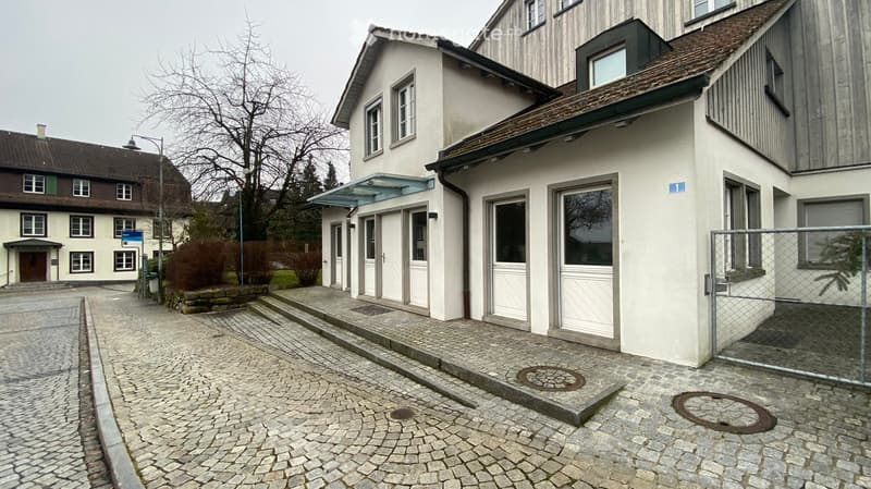 Cobblestone street, white building, several doors, windows, canopy