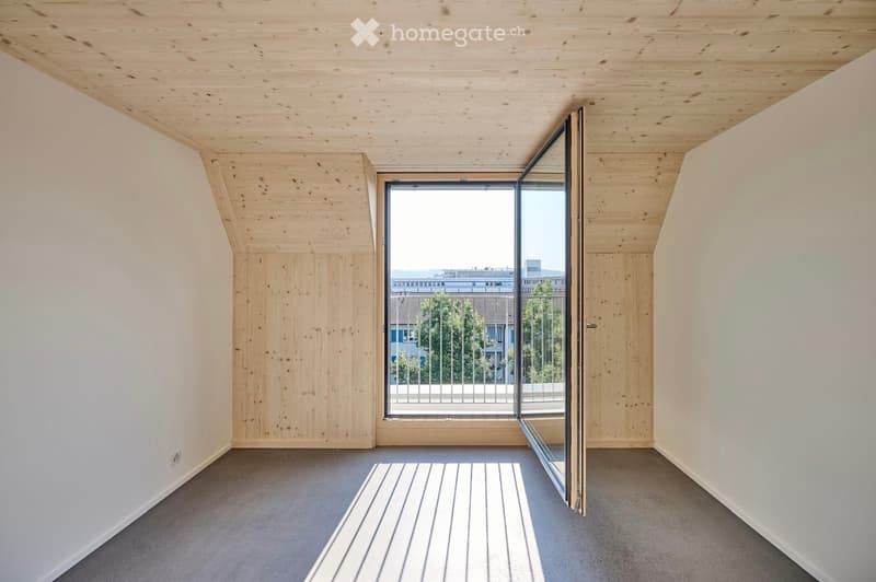 Empty room with wooden ceiling, white walls, grey carpeted floor, and large sliding glass door leading to a balcony.