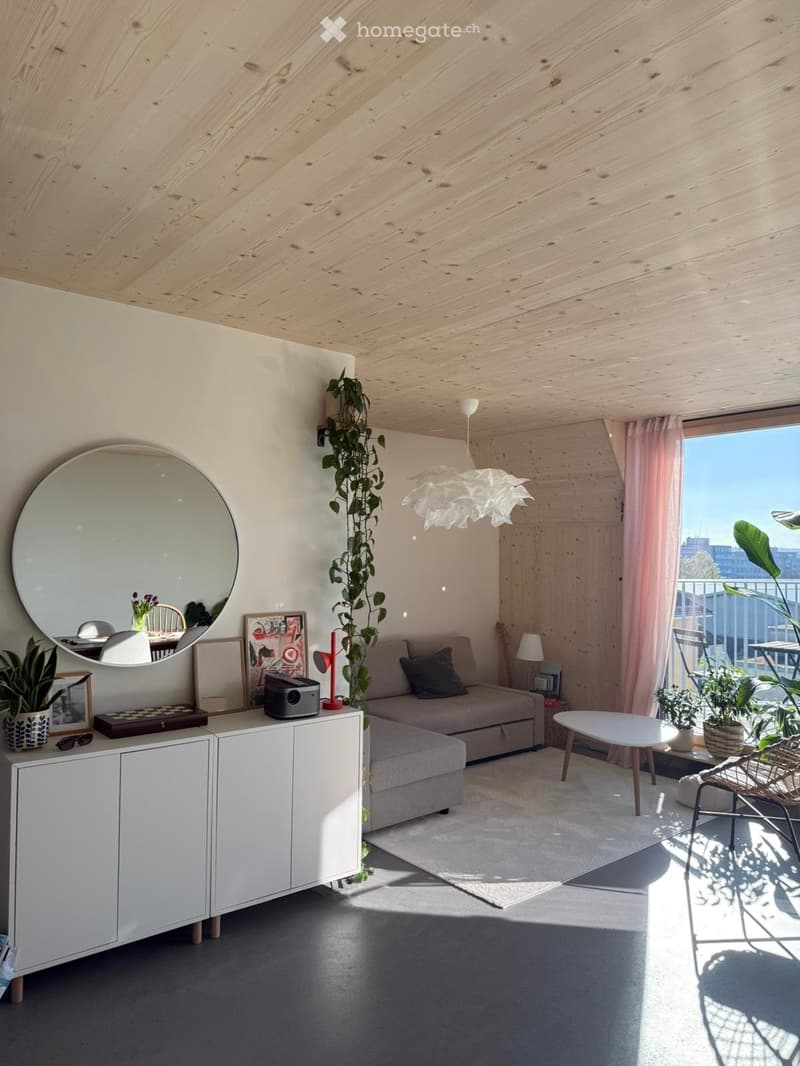 Modern living room with wooden ceiling, large window with view, sofa, coffee table, cabinet, mirror, and plants.
