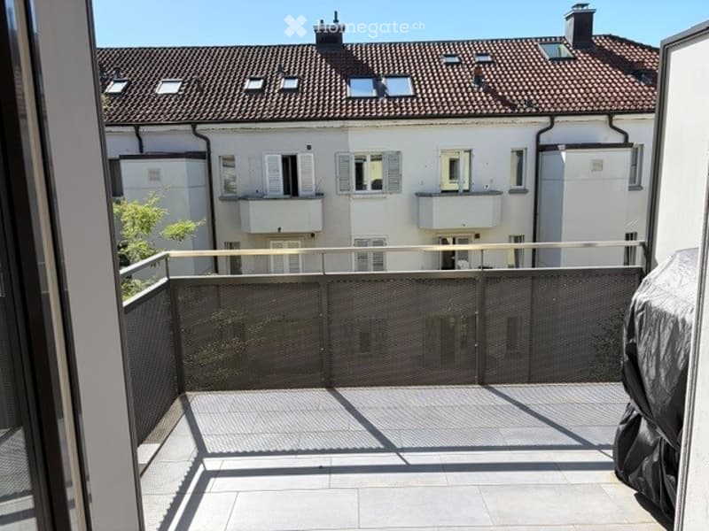 Balcony with metal railing, tiled floor, and view of neighboring buildings with balconies and windows.