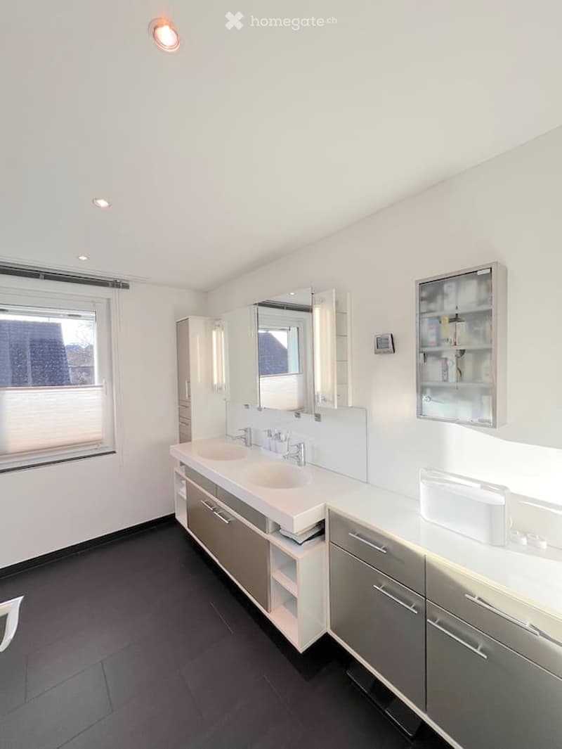 Modern bathroom with double sink, mirrored cabinet, and built-in storage. Features a large window with blinds and recessed lighting.