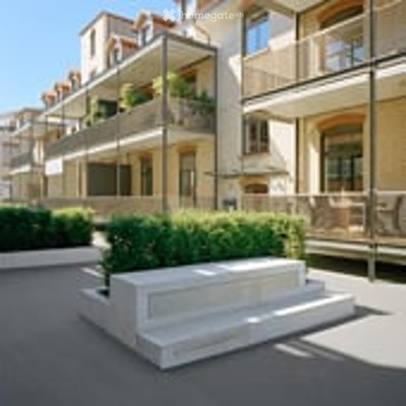 Modern apartment building with balconies, white concrete planter, paved courtyard