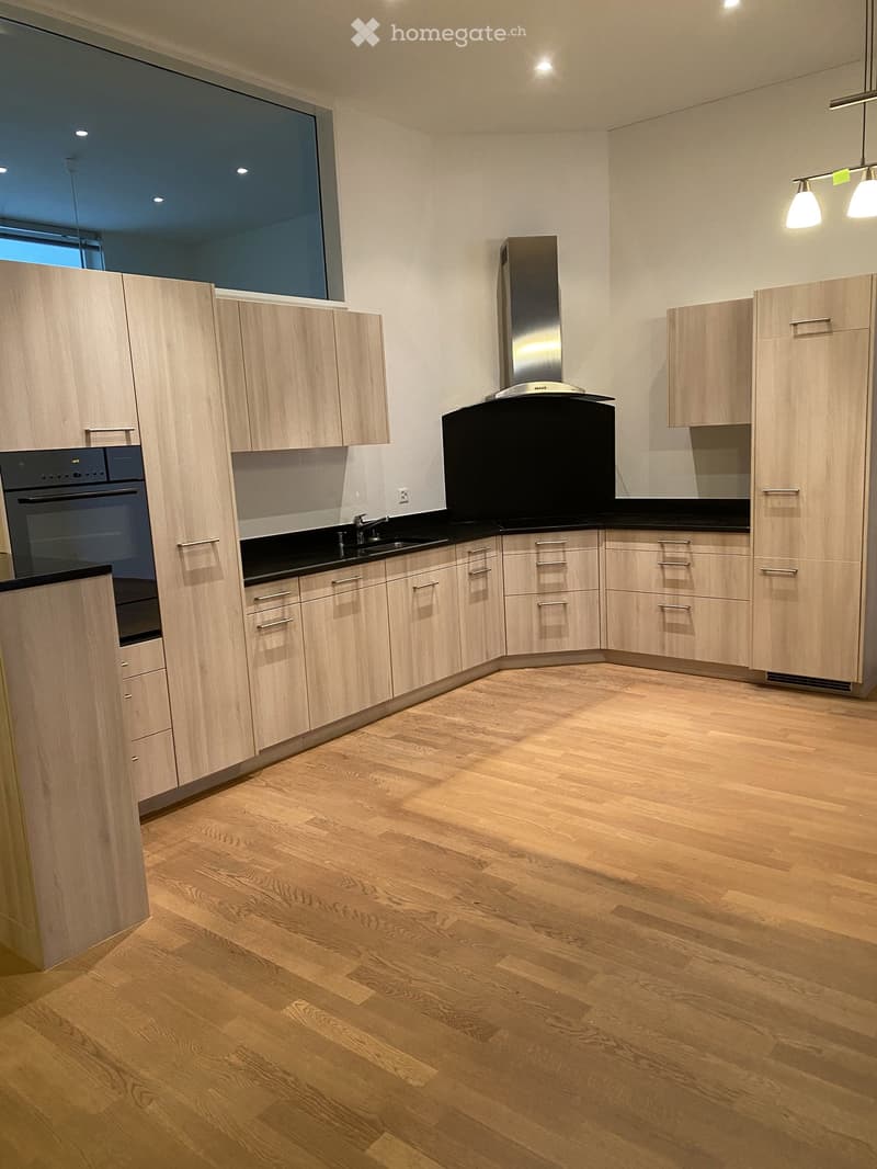 modern kitchen with wooden cabinets, black countertops, stainless steel appliances, large window