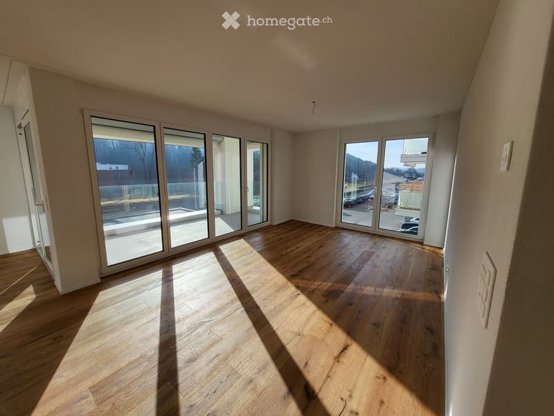 Empty room with wooden flooring and large glass sliding doors leading to a balcony area.