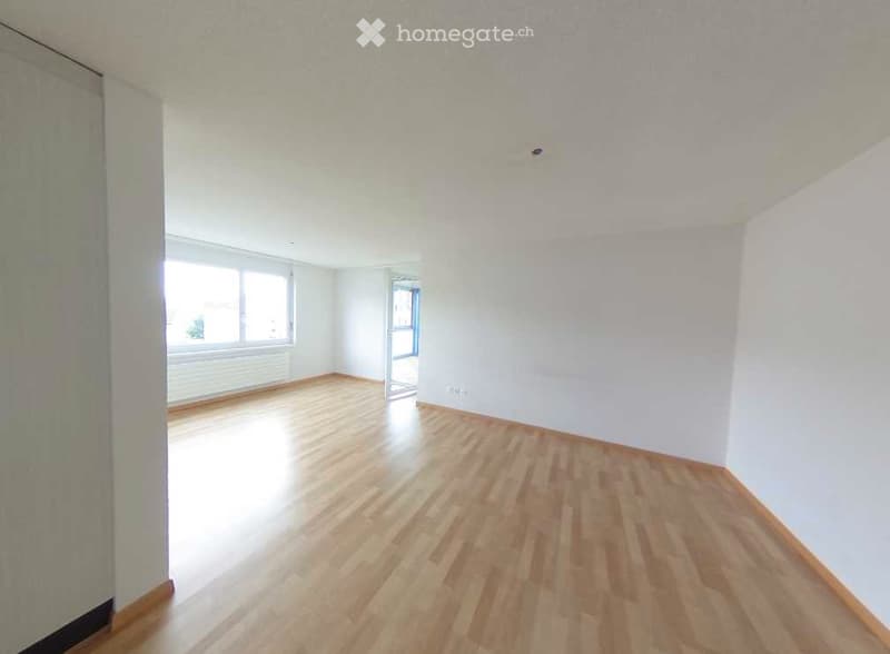 Empty room with wooden flooring, white walls, and large windows allowing natural light. No furniture or equipment present.