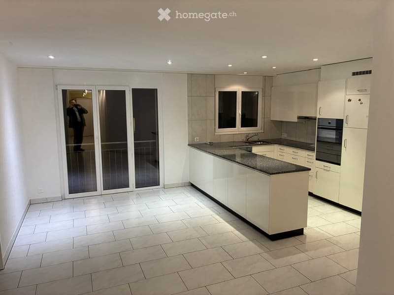 Modern kitchen with white cabinets, a central island, and a black countertop. Features include a sink, faucet, and an oven.