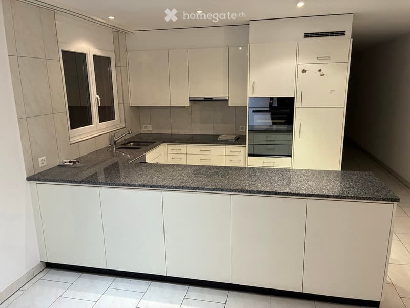 Modern kitchen with white cabinets, granite countertop, sink, and built-in oven.