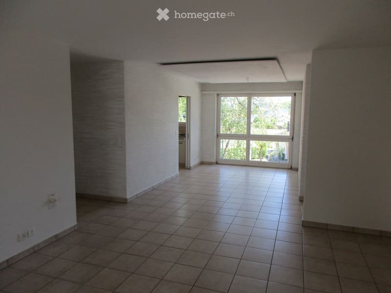 Empty room with tiled floor, white walls, and large sliding glass door leading to outdoor area.