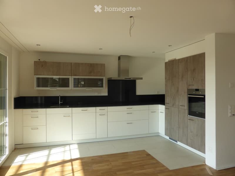 Modern kitchen with white and wood cabinets, stainless steel appliances, and a black countertop.