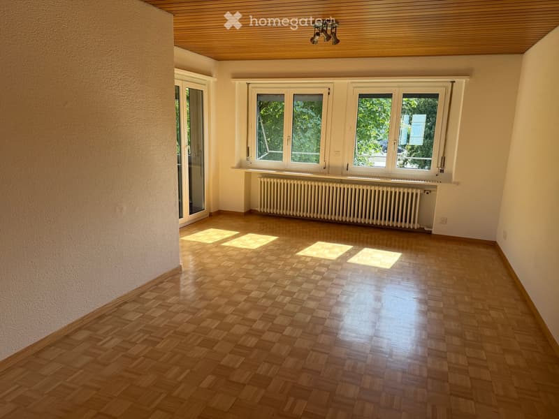 Empty room with wooden flooring, large windows, radiator, and wooden ceiling.
