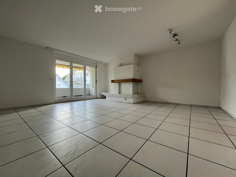 Empty room with tiled floor, white walls, large sliding glass doors, and a built-in fireplace with a wooden shelf.
