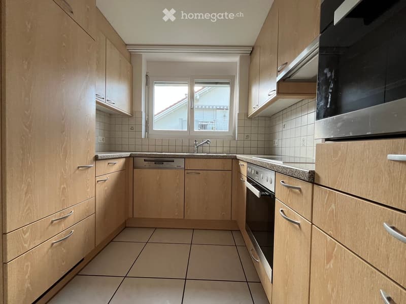 Modern kitchen with light wooden cabinets, tiled walls, granite countertops, and stainless steel appliances including a sink, dishwasher, oven, and microwave.