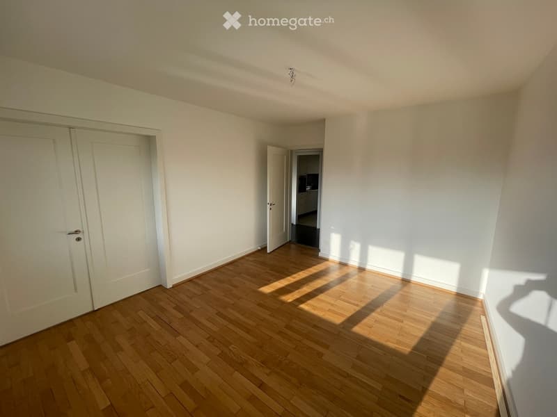 Empty room with wooden flooring, white walls, and two doors leading to other spaces.