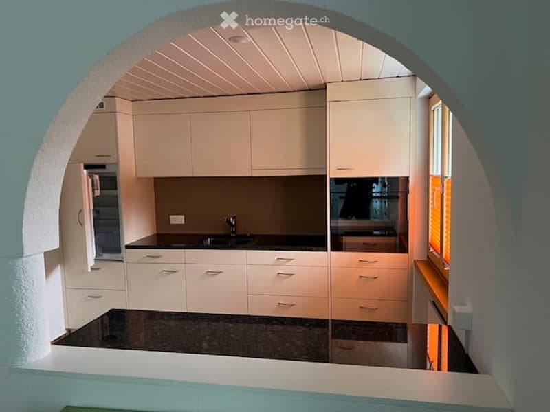 White cabinets, black countertops, modern appliances, open archway, minimalist design