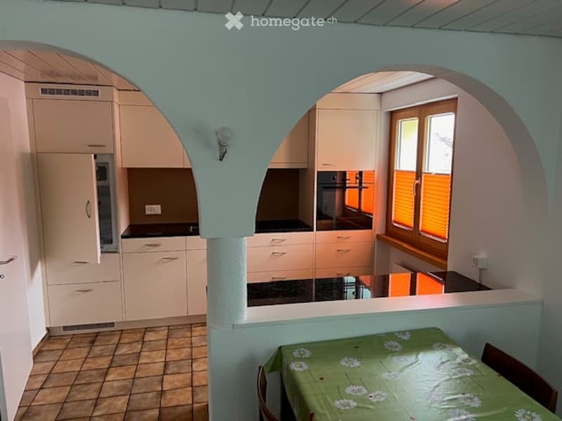 kitchen, arch shaped open structure, dining table, tiled floor, window with orange blinds, kitchen appliances