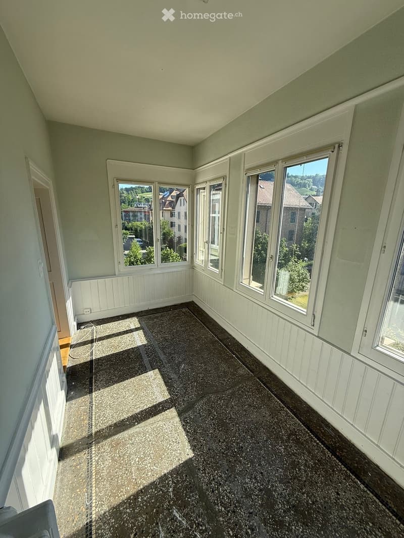 Empty room with large windows, light green walls, and a speckled floor. No furniture or equipment present.