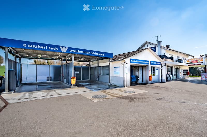 A commercial building labeled "Waschcenter Hörhausen" with a covered area for washing machines, a small shop entrance, and signage indicating textile washing services.