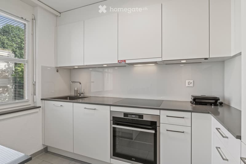 Modern kitchen with white cabinets, stainless steel appliances, and a sleek countertop.